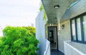 A narrow outdoor corridor with a brick wall on one side and a white railing on the other. - Green Peace Da Nang (Da Nang)