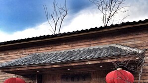 A traditional wooden building with a tiled roof, a wooden door, and two red lanterns. - Beijing Eastern Library Hotel (Huairou)