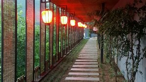 A corridor with a red ceiling, a stone pathway, and hanging lanterns. - Beijing Eastern Library Hotel (Huairou)