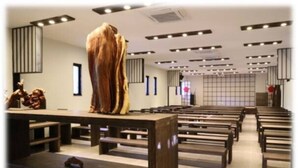 A modern interior with wooden benches arranged in rows, a central sculptural piece, and a grid-patterned wall. - Beijing Eastern Library Hotel (Huairou)