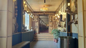 A hallway with wooden paneling, a bench, a large metal pot, and wall-mounted lights. - Beijing Eastern Library Hotel (Huairou)