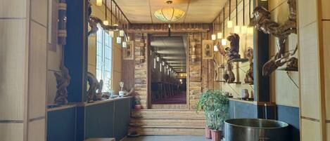 A hallway with wooden paneling, a bench, a large metal pot, and wall-mounted lights.