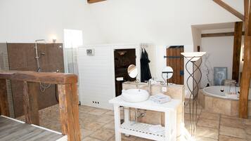 A bathroom with a wooden vanity, a sink, a mirror, a bathtub, and a floor lamp.
