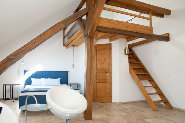 Un dormitorio con una cama, una bañera blanca, una escalera de madera y una puerta de madera.