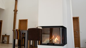 Una habitación amplia con una chimenea moderna, vigas de madera y un techo alto.