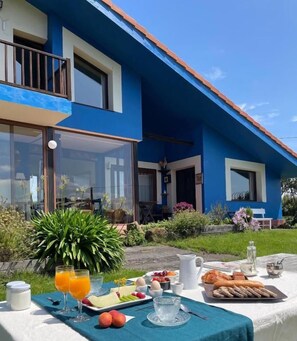 A breakfast setup on a terrace with a table, food, and drinks. - Hotel y Apartamentos Son de Mar (Villaviciosa)