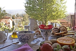 A table set with tea cups, a sugar bowl, a teapot, and pastries, with a view of trees and buildings in the background. - Hotel y Apartamentos Son de Mar (Villaviciosa)