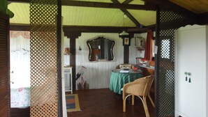 A room with a wooden ceiling, a green table, a wicker chair, and a mirror on the wall. - Hotel y Apartamentos Son de Mar (Villaviciosa)