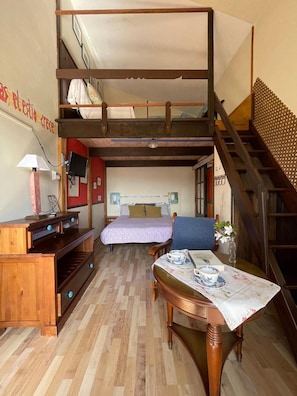 A compact room with a bunk bed, a desk with a lamp, a chair, and a small table with cups. - Hotel y Apartamentos Son de Mar (Villaviciosa)