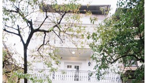 Un bâtiment à la façade en bois, avec une entrée bien visible et un vélo décoré de fleurs devant.