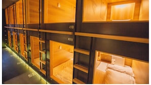 Une rangée de lits superposés dans une chambre d’hôtel, chacun étant muni d’un numéro au-dessus.