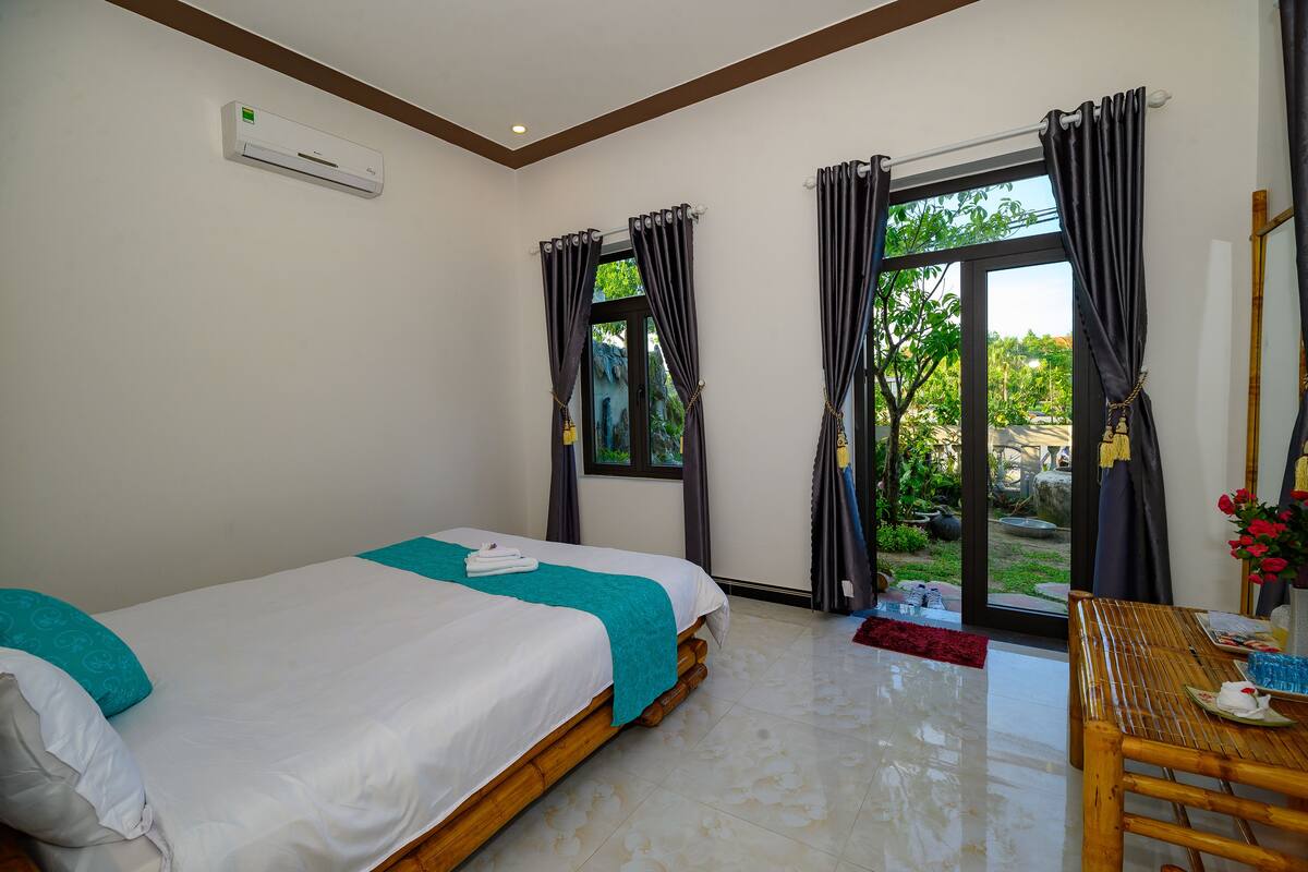 A hotel room with two beds, a wooden table, and a view of the outdoors.