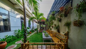 A courtyard with a wooden bench, potted plants, and a pathway. - Hoi An Garden Sea Homestay (Da Nang)