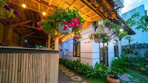 A rustic outdoor area with a bamboo fence, potted plants, and hanging flower baskets. - Hoi An Garden Sea Homestay (Da Nang)