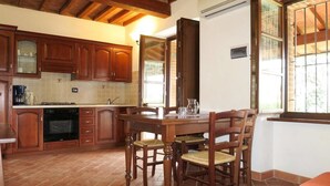 Una cocina con armarios de madera, una mesa de comedor con sillas y una ventana con vistas.