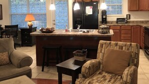 A modern kitchen with a central island, pendant lighting, and wooden cabinets.