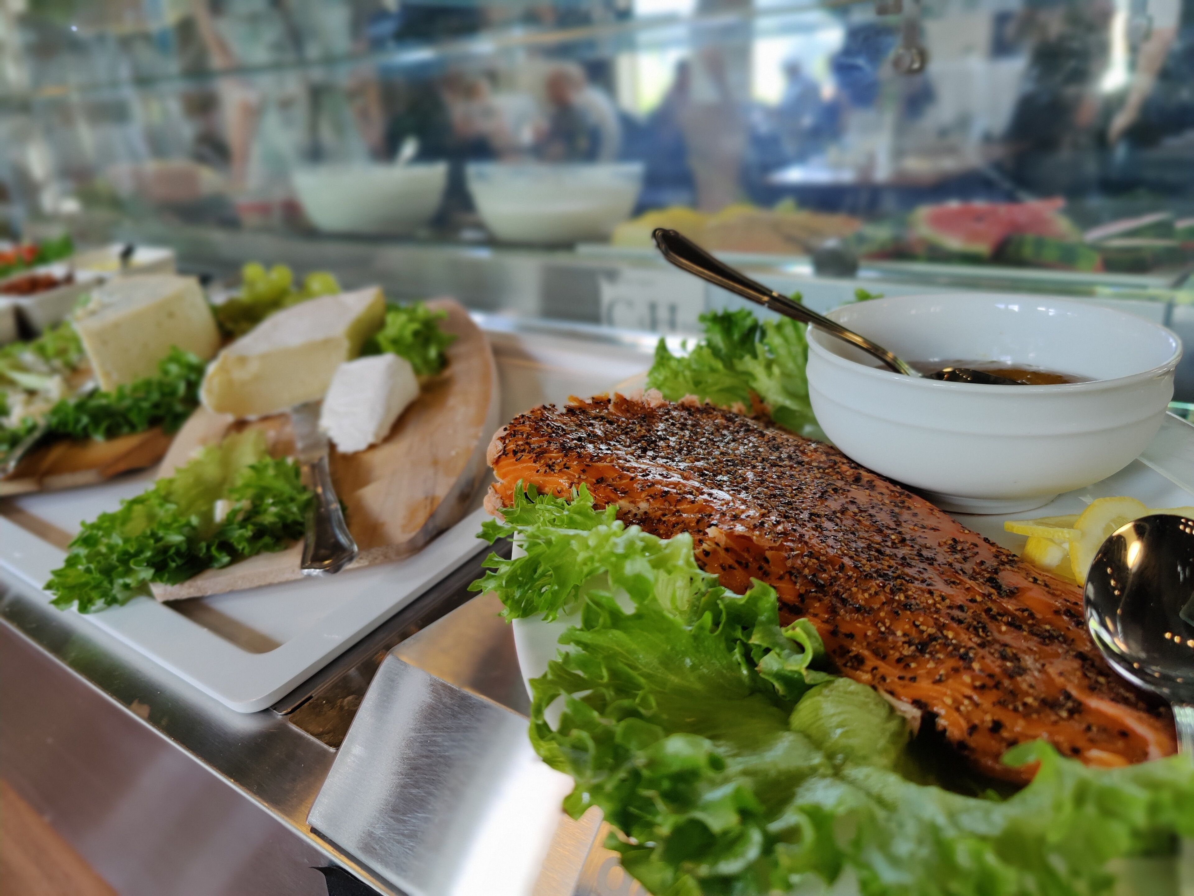 A buffet with various dishes including salmon, cheese, and vegetables.