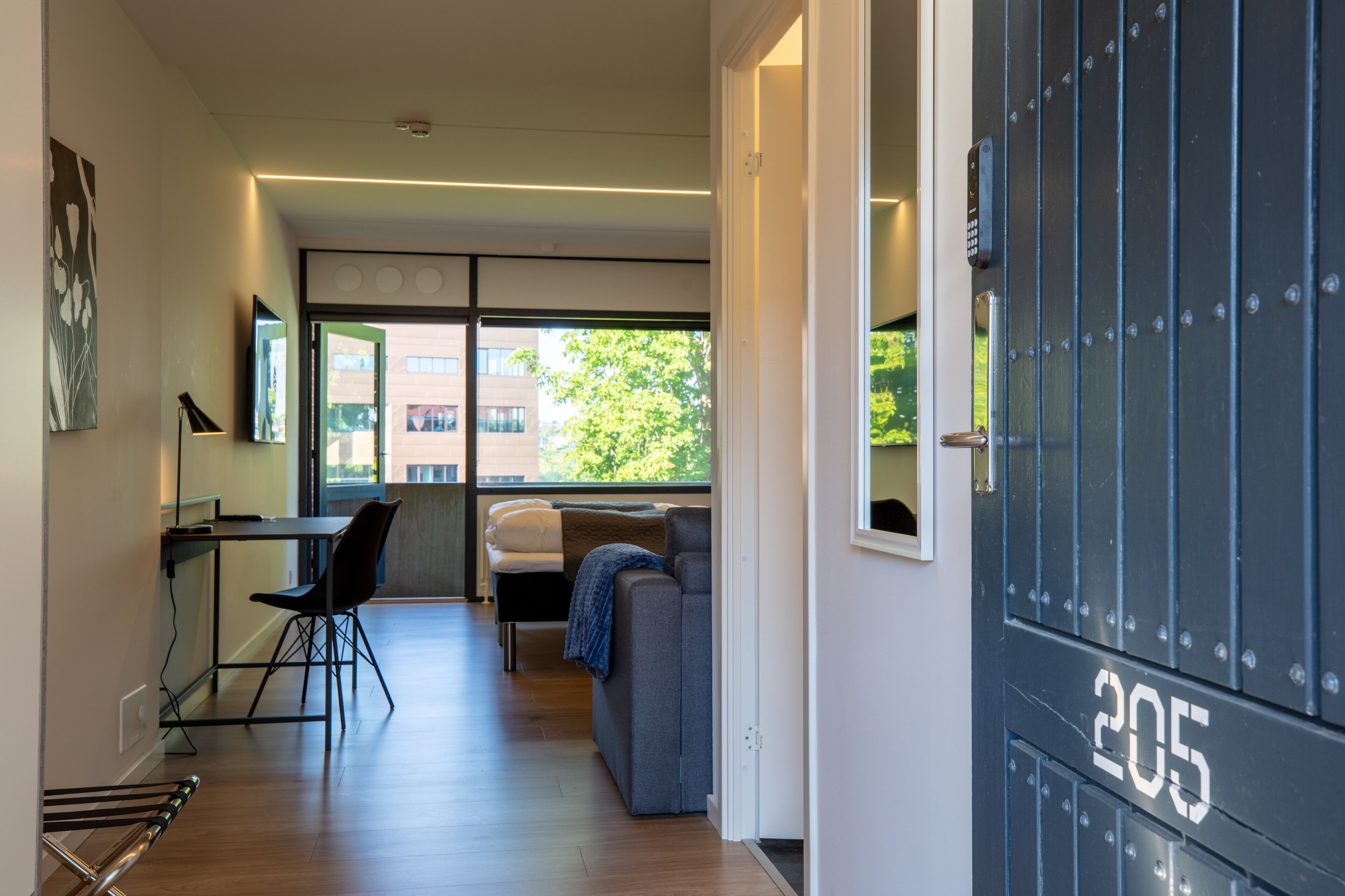 Un interior moderno con comedor, sofá y una puerta con el número 205.