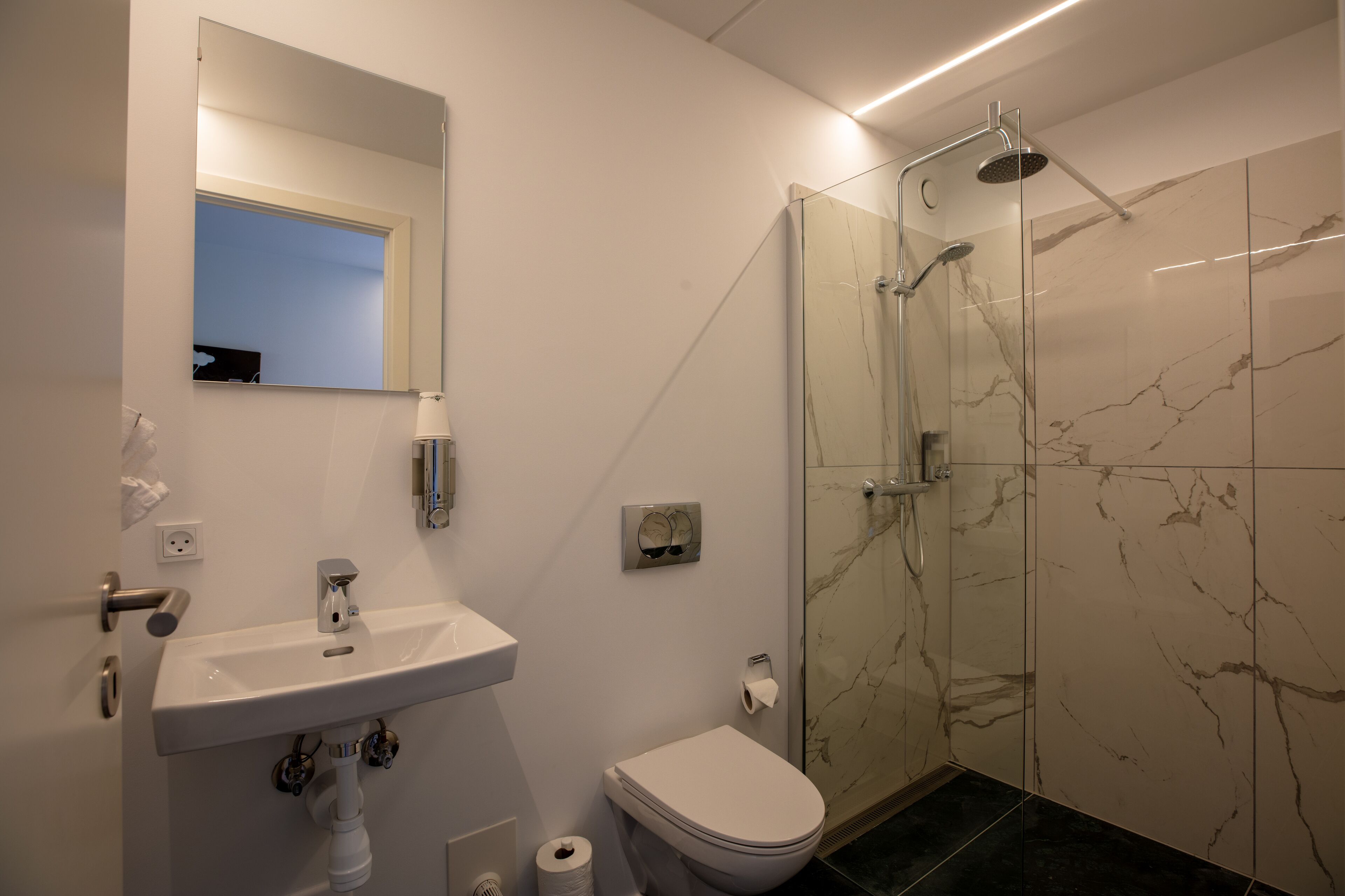A bathroom with a sink, toilet, and a glass-enclosed shower.