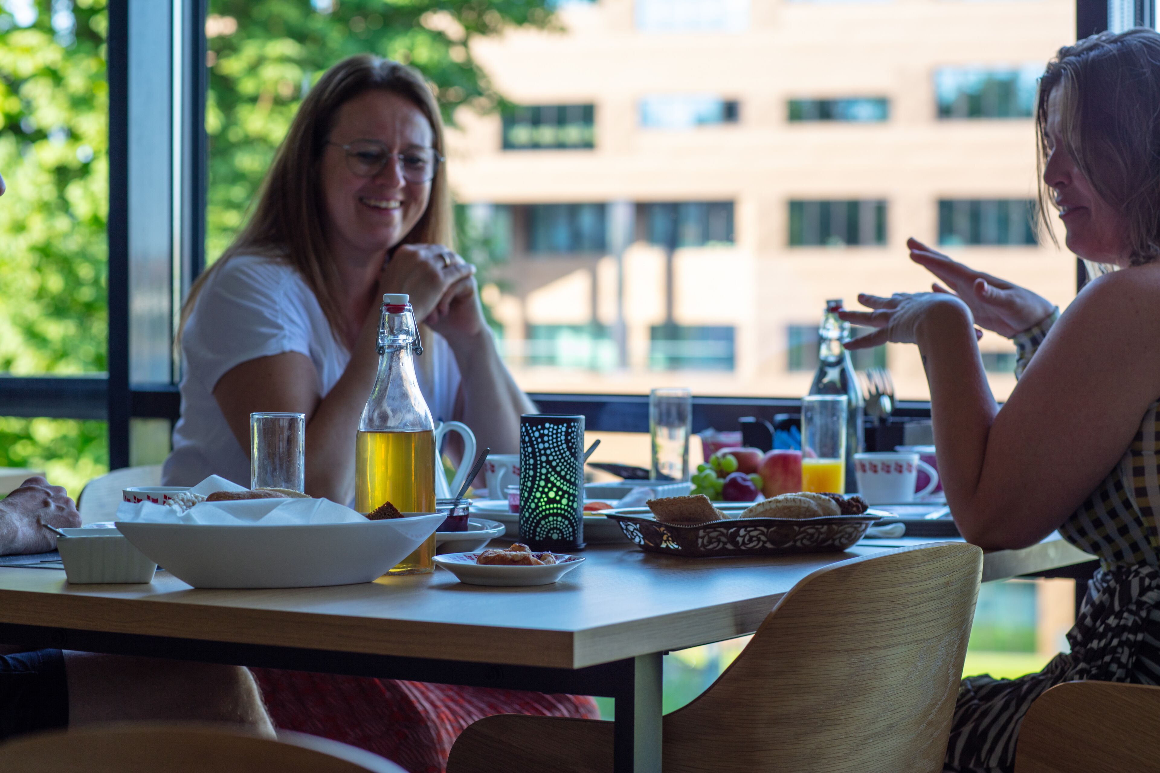 A dining table with breakfast items, a bottle of juice, and a pitcher.