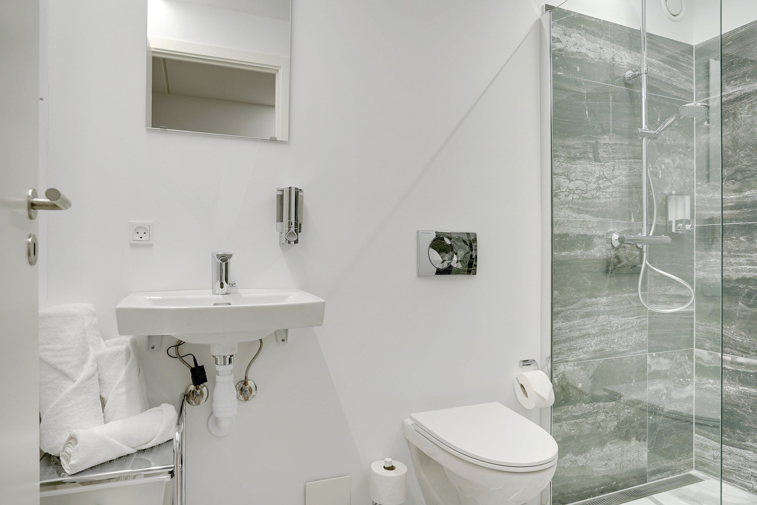 A modern bathroom with a glass shower enclosure, a white sink, and a toilet.