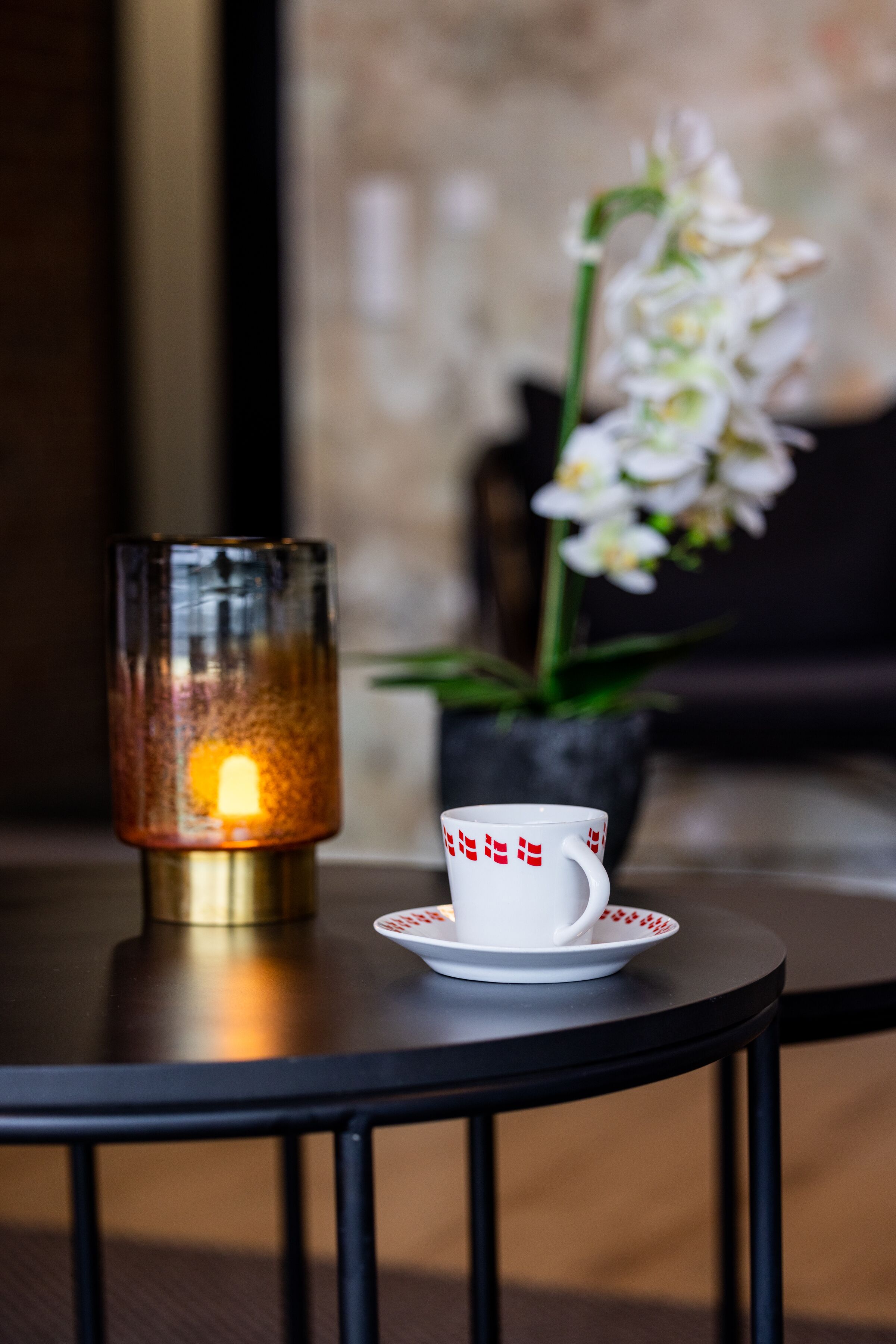 A table with a candle holder and a cup on a round table.