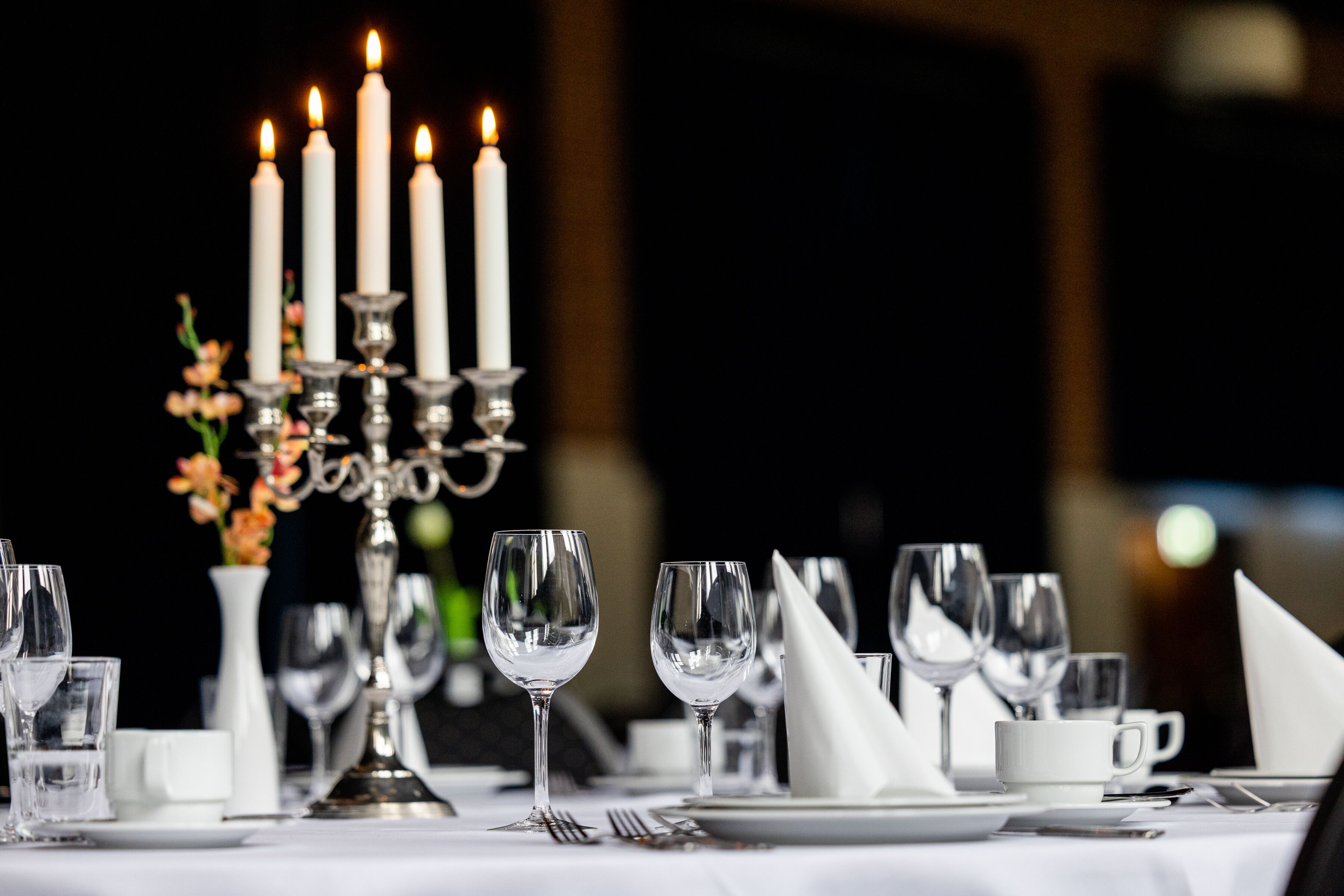 A table set for dining with candles, glasses, and a vase of flowers.