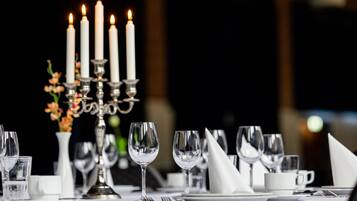 A table set for dining with candles, glasses, and a vase of flowers.