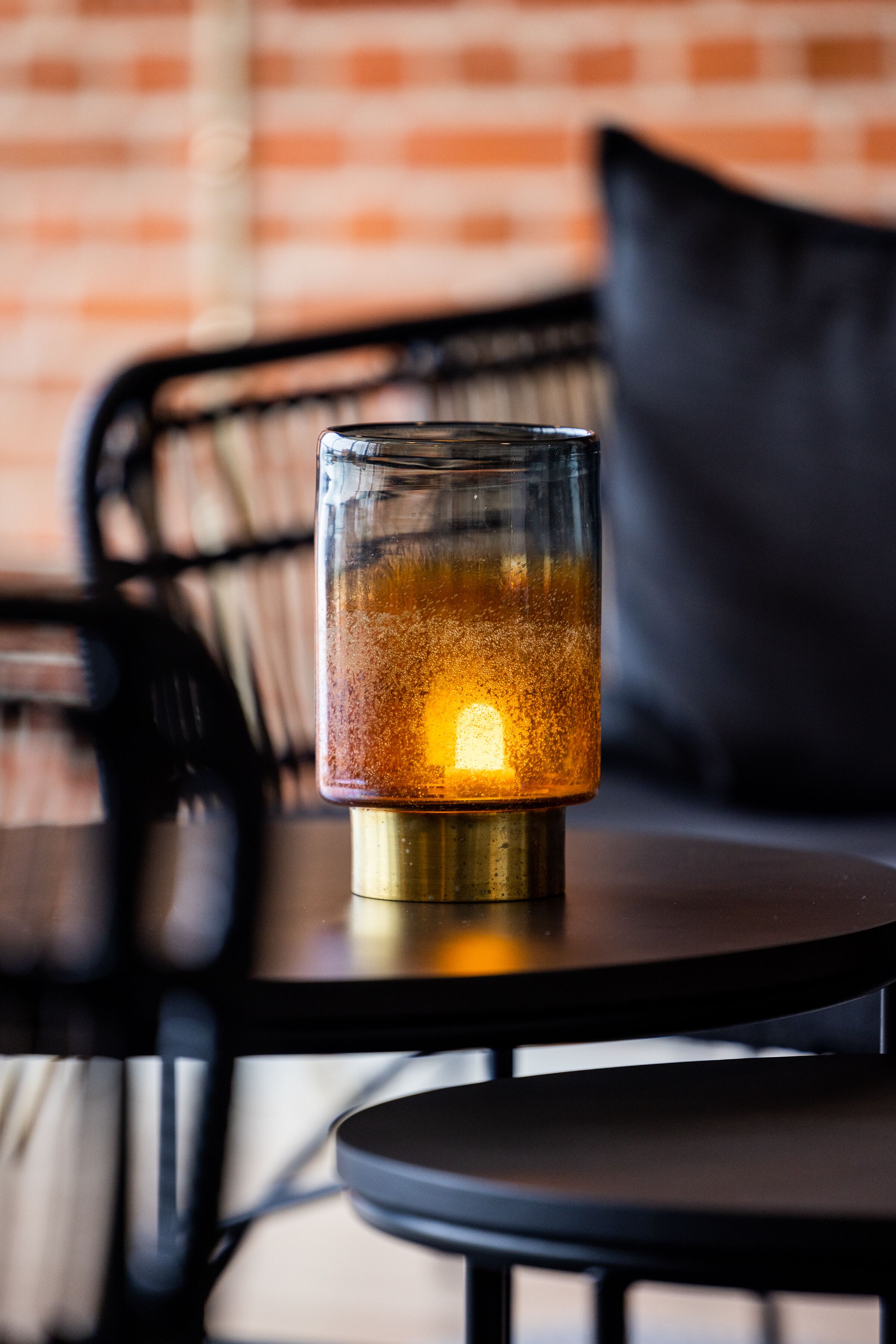 A candle in a glass holder on a round table.