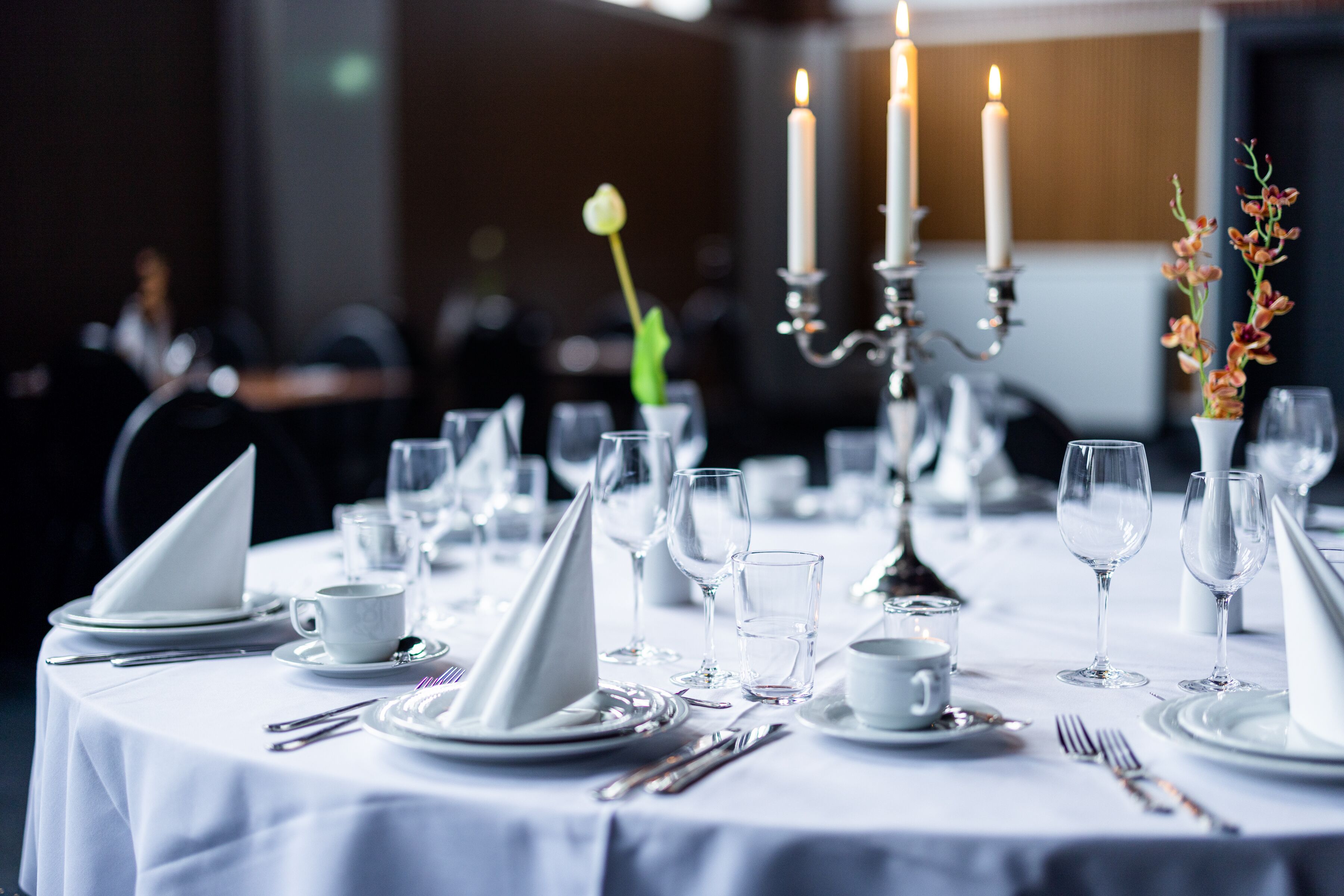 Une table dressée pour un dîner formel, avec des nappes blanches, des couverts en argent et des chandeliers.