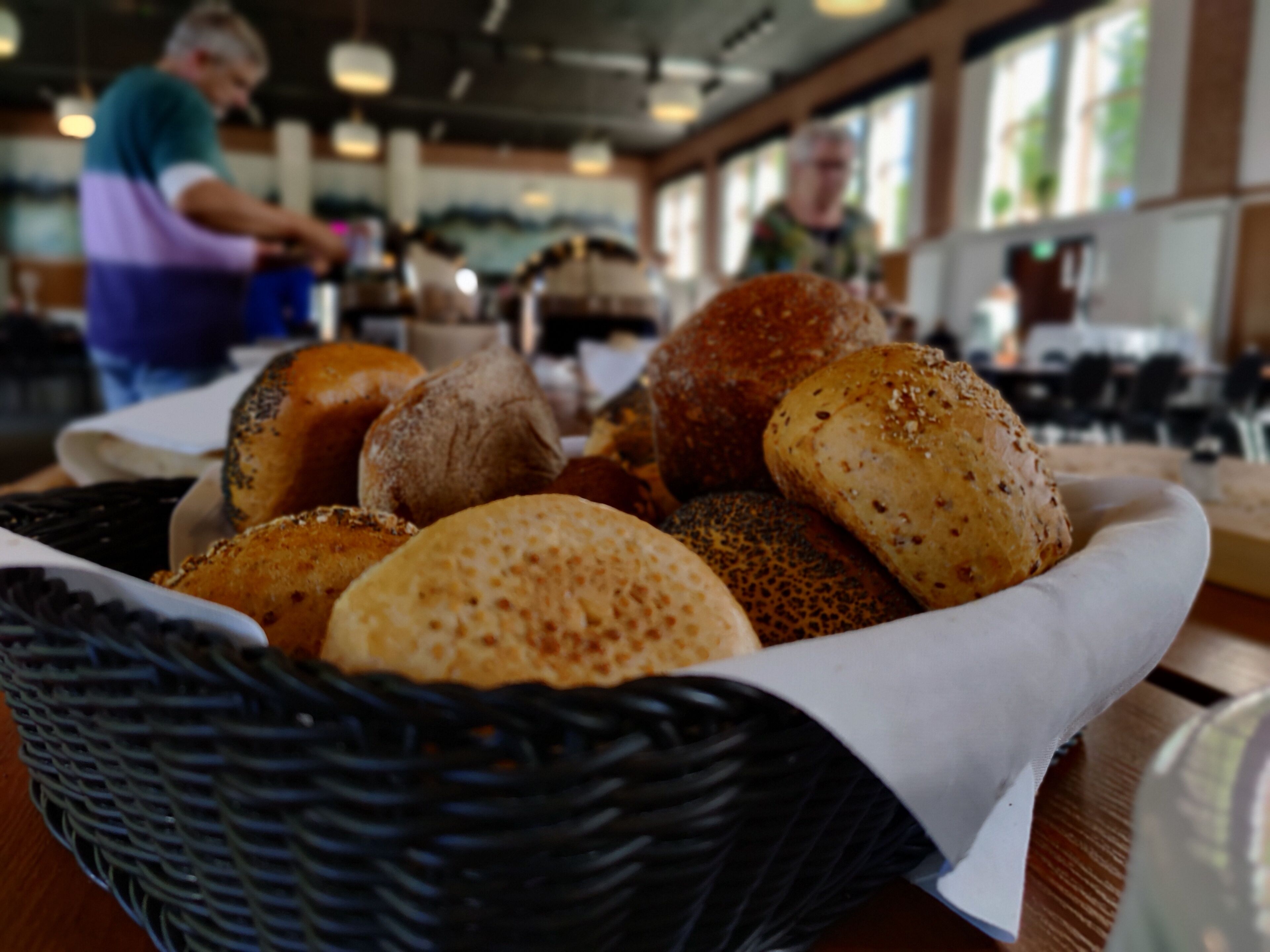 A basket of various breads on a table in a restaurant.
