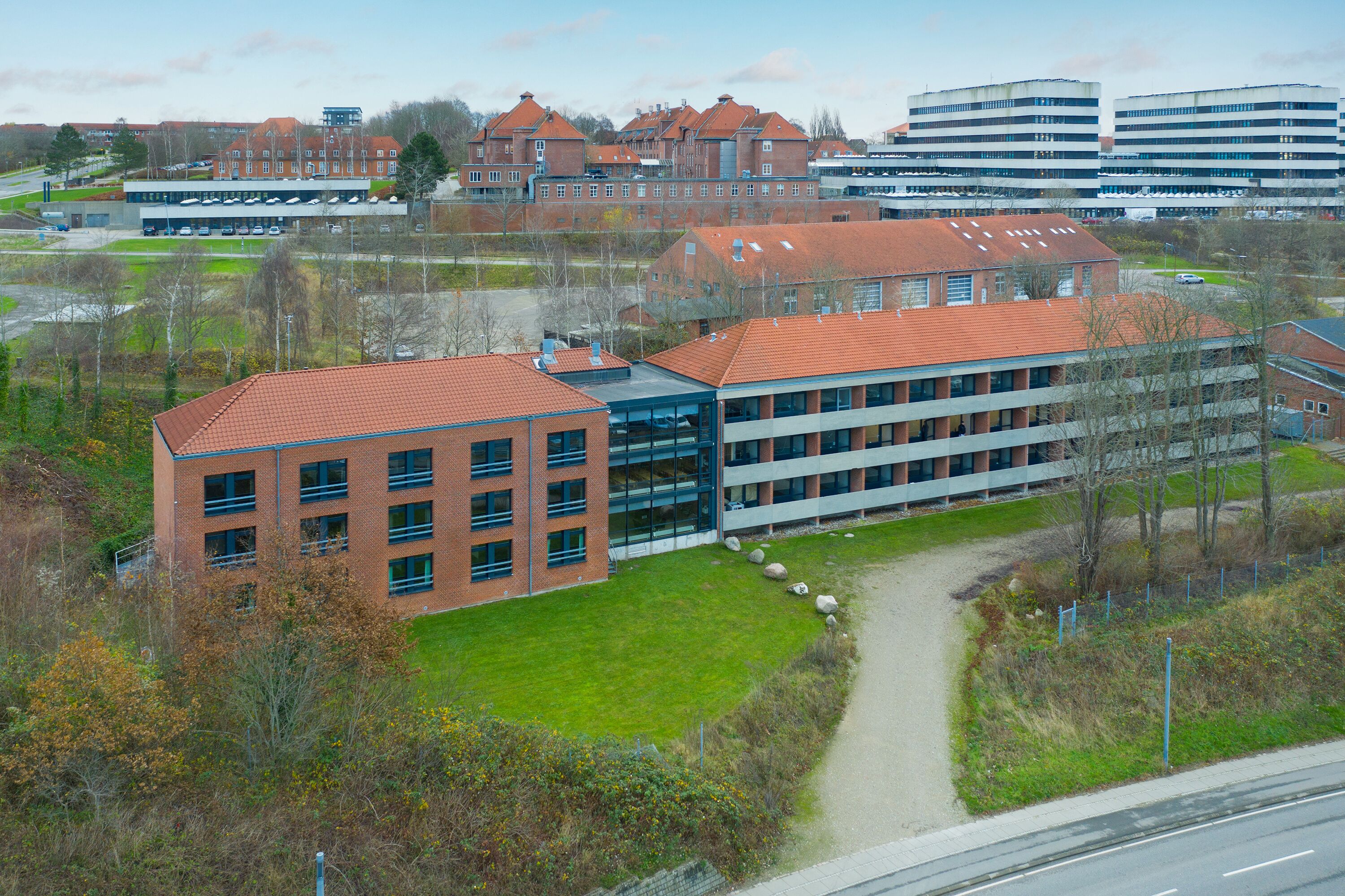 A modern building complex with multiple buildings, including a large brick structure and a glass-fronted building.