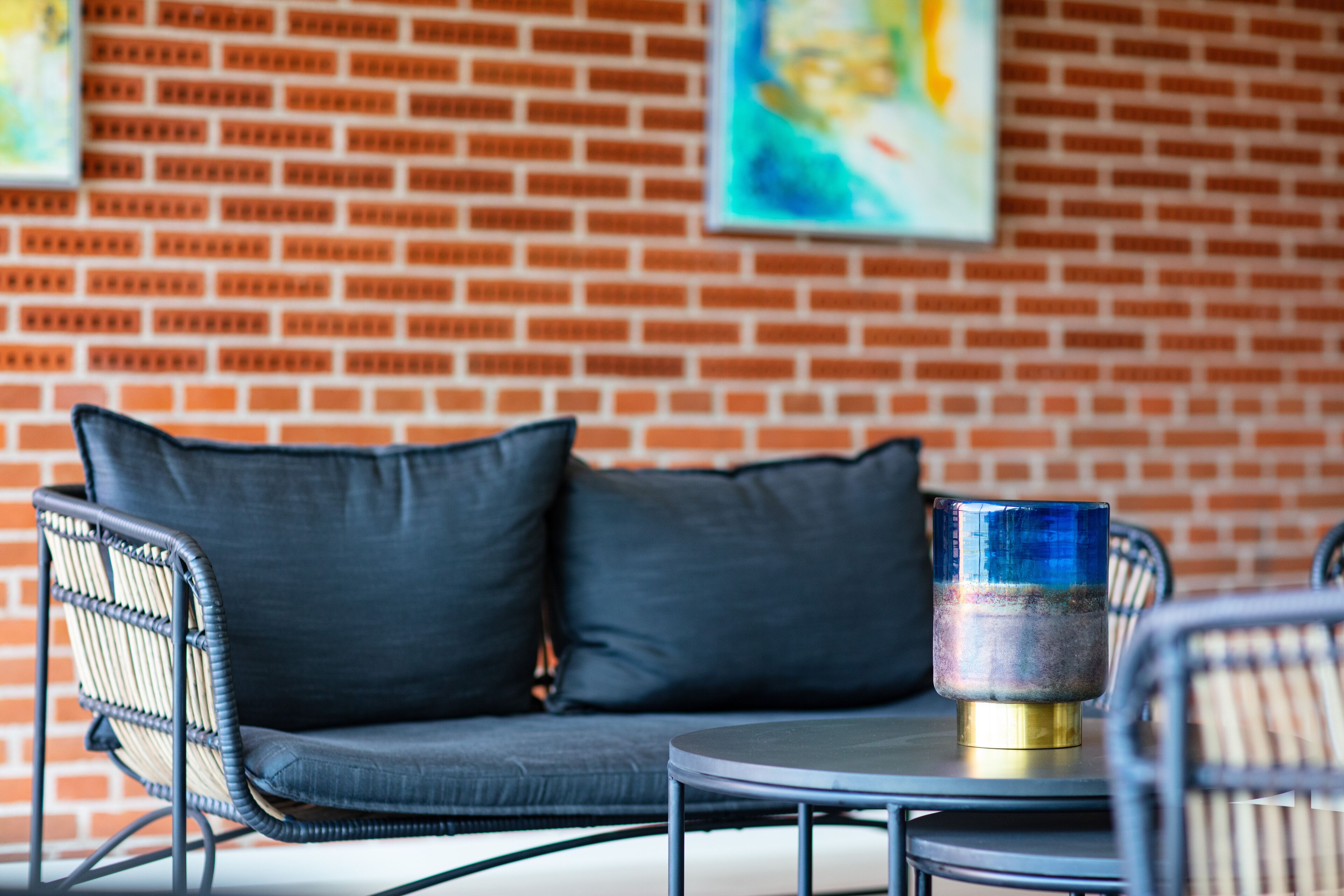 A brick wall with a sofa and chairs, a round table, and a decorative glass object.