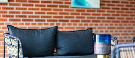 A brick wall with a sofa and chairs, a round table, and a decorative glass object.