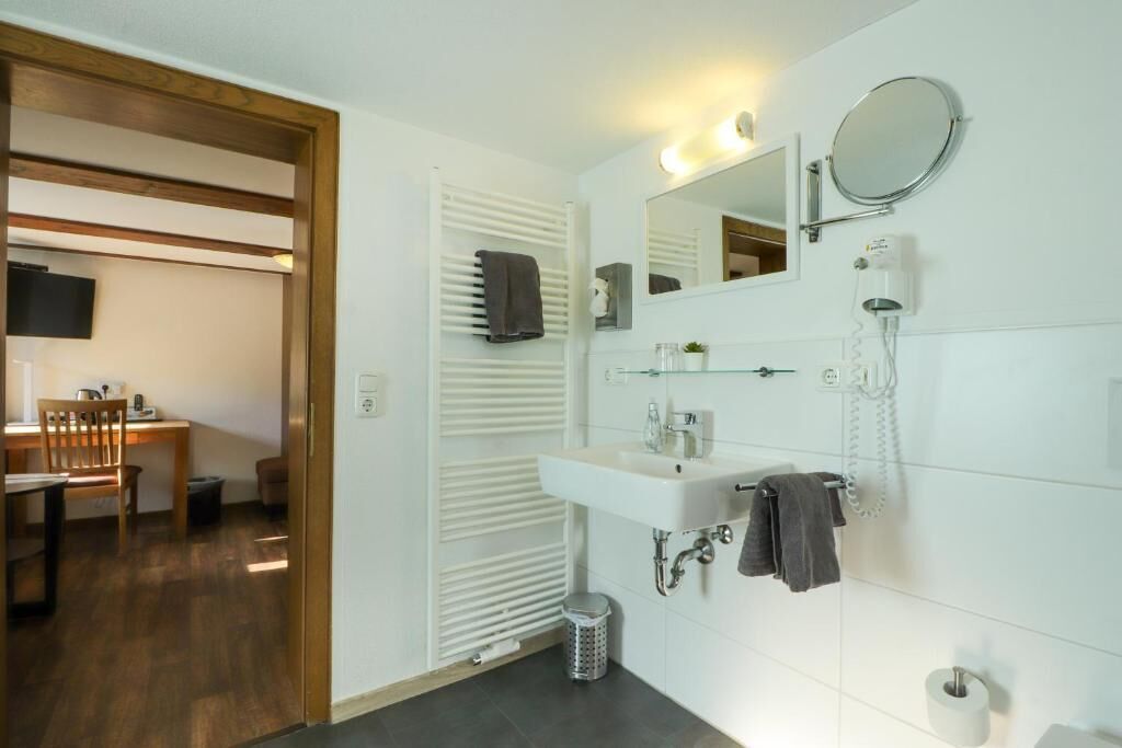 A modern bathroom with a white sink, mirror, and towel rack.