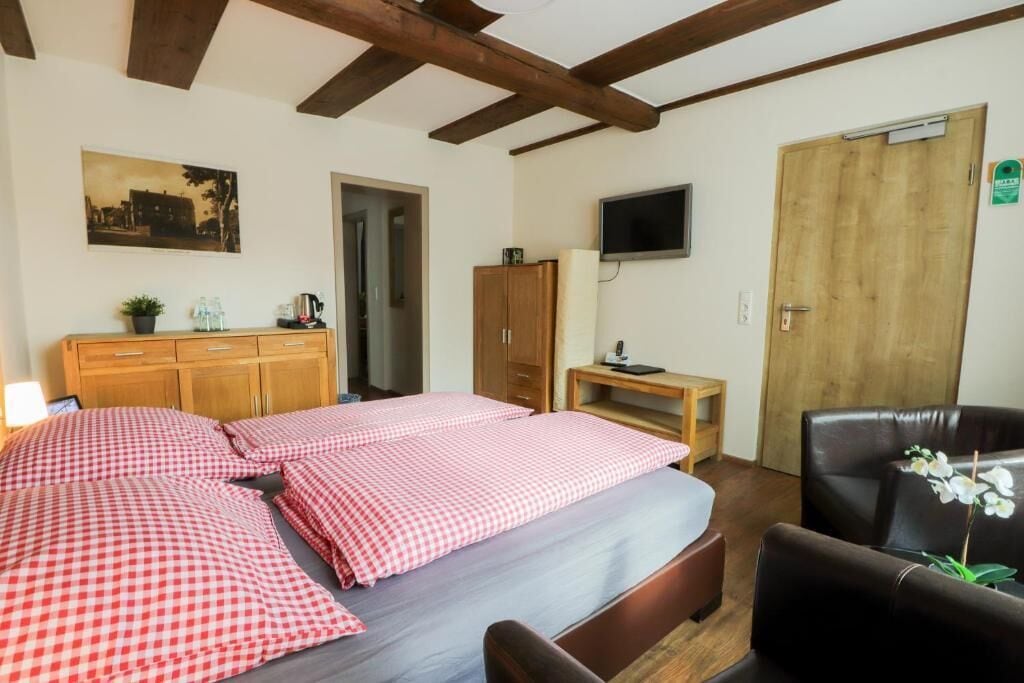 A bedroom with two beds, a wooden wardrobe, a television, and a door with a sign.