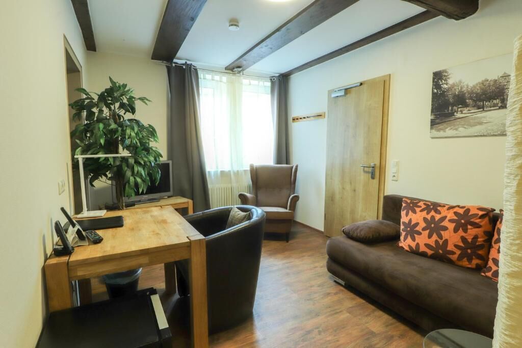 A living room with a wooden table, a sofa, a chair, and a television.