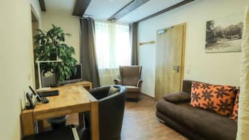 A living room with a wooden table, a sofa, a chair, and a television.