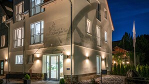 Een hotel met een moderne gevel, meerdere ramen en een goed verlichte ingang.