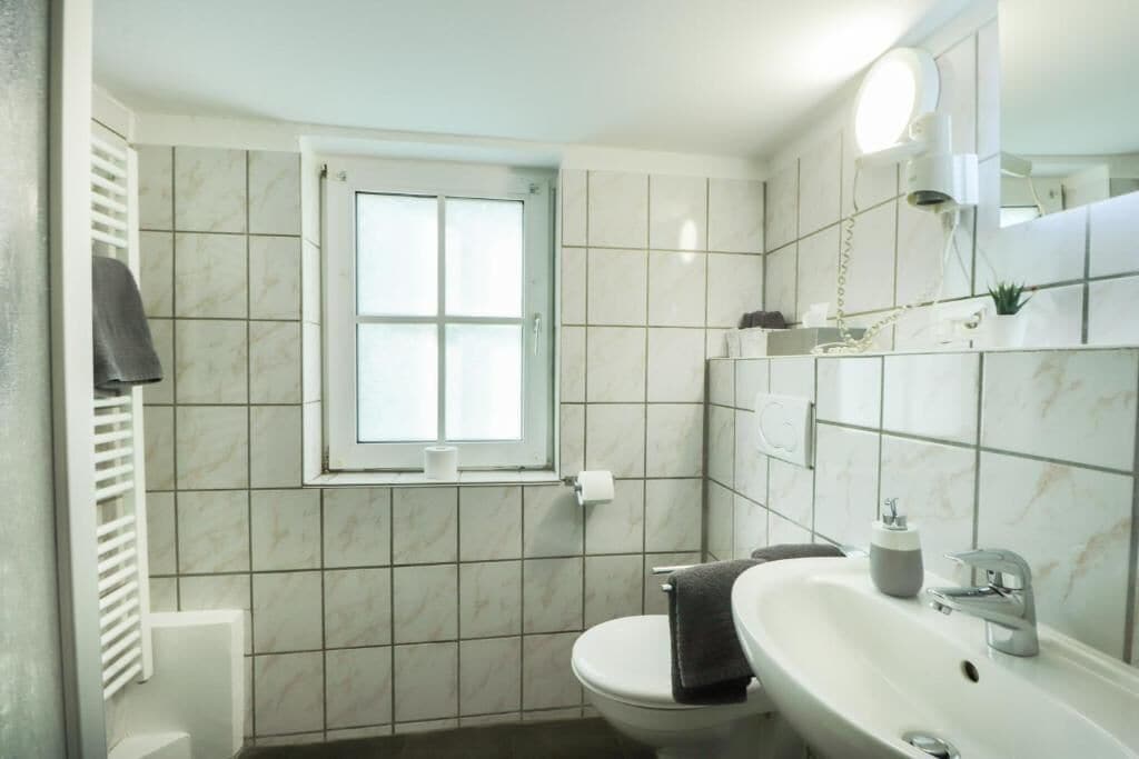 A bathroom with a toilet, sink, and window.