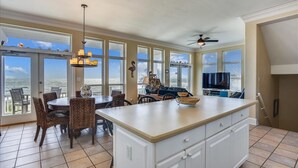 A spacious kitchen with a large island, dining area with wicker chairs, and a view of the ocean through large windows. - LET AN IRISH SEABREEZE WISK YOUR CARES AWAY! (St. George Island)