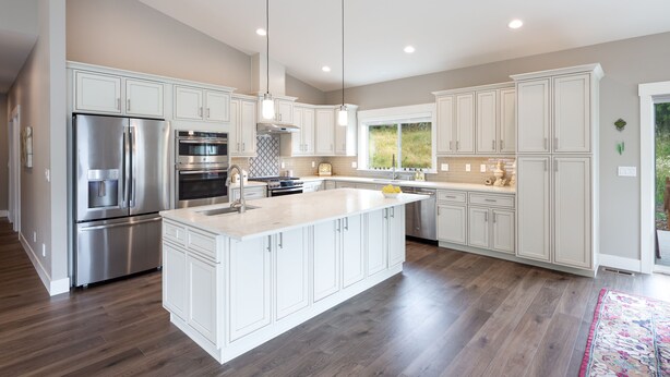 A modern kitchen with white cabinetry, stainless steel appliances, and a large island. - Beautiful newer home in Sudden Valley offering stunning lake view, golf and more (Bellingham)