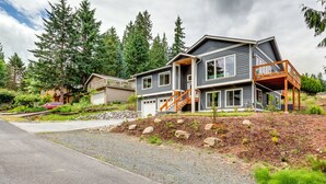 A two-story house with a covered porch and a staircase leading to a deck. - Beautiful newer home in Sudden Valley offering stunning lake view, golf and more (Bellingham)
