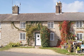 A stone building with a white door, windows, and a chimney.