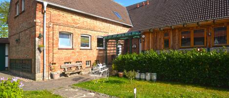 A brick building with a green awning, a wooden bench, and a stone pathway.
