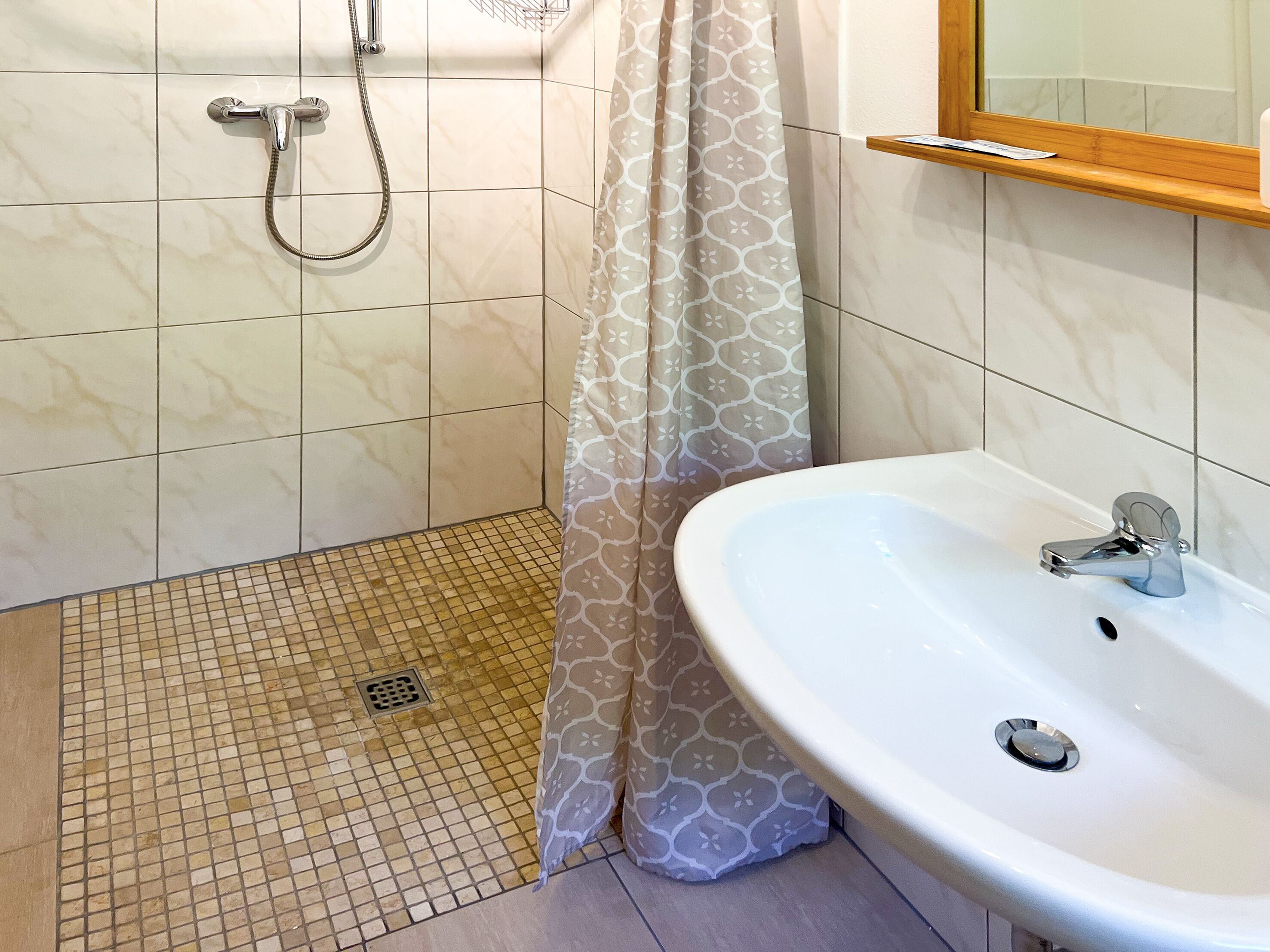 A bathroom with a shower, a sink, and a patterned shower curtain.