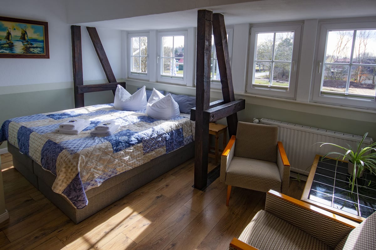 A bedroom with a bed, a chair, a window, and a radiator.