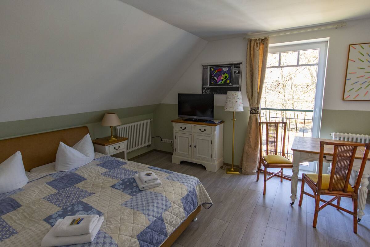 A bedroom with a bed, a television, a desk, and a chair.