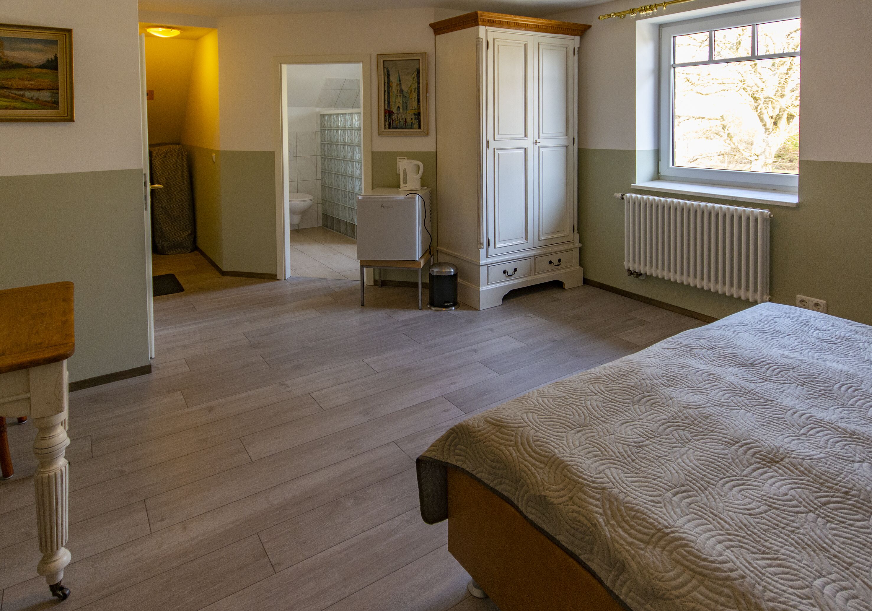 Ein Schlafzimmer mit Bett, Kleiderschrank, Heizkörper und Fenster.