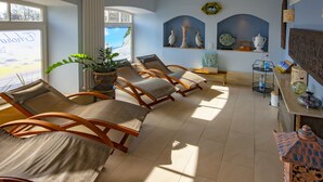 A sunlit room with four wooden lounge chairs, a potted plant, and a view of the beach through a window. - Himmelreich Rügen (Zirkow)